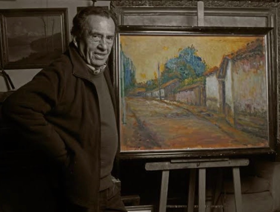 Waldo Nahuel in his studio, beside one of his paintings